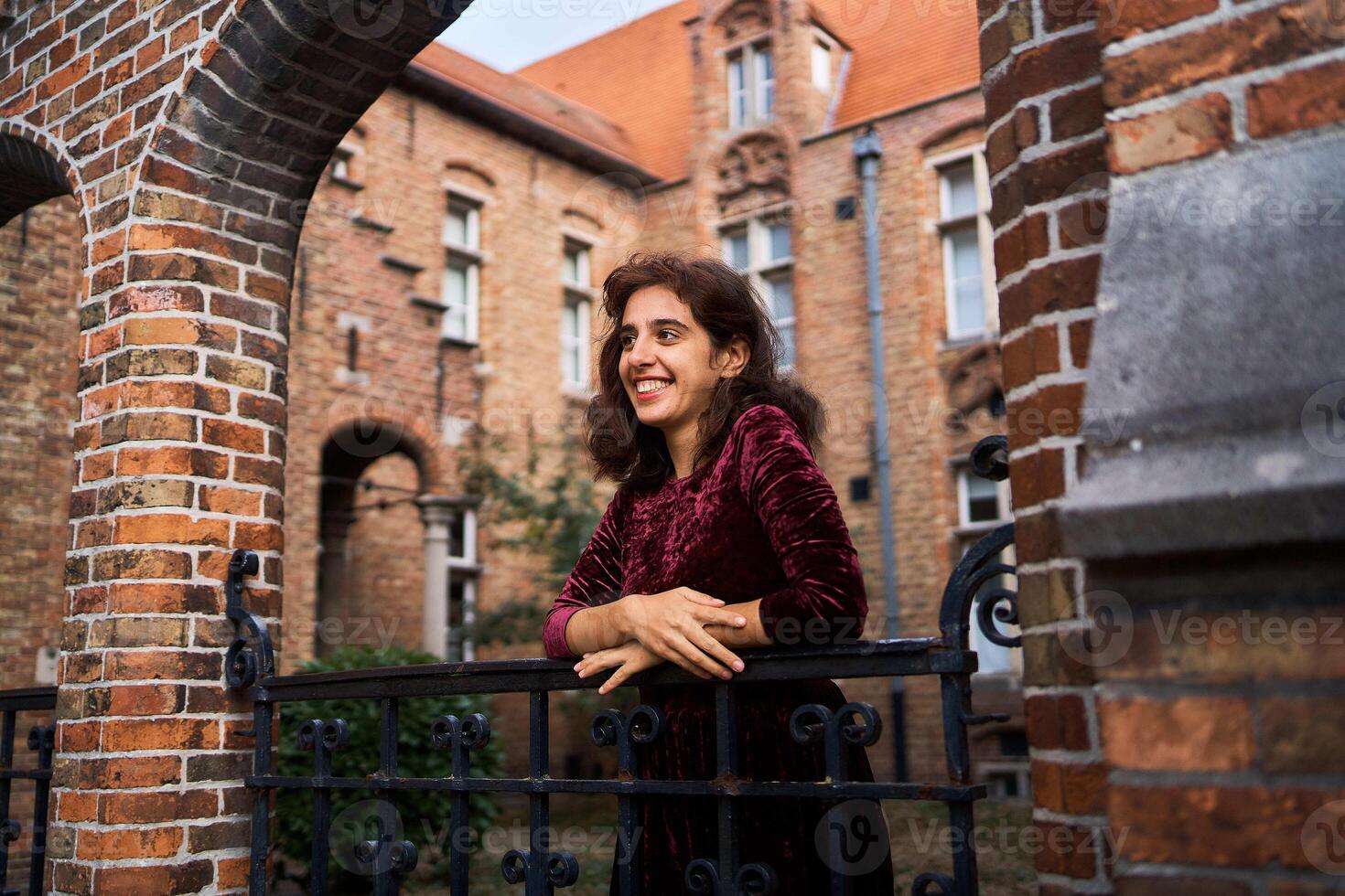 a girl in a red corduroy dress with an open back walks through the streets of Bruges on an autumn day photo