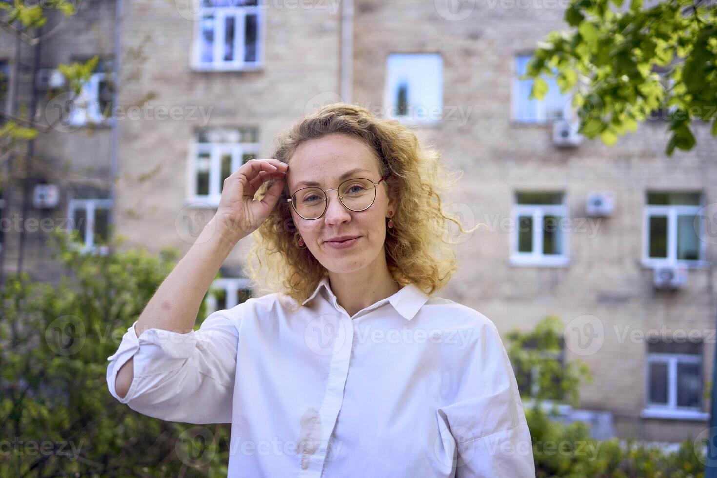 middle age woman in 70s, 80s style clothes with a coffee stain on her blouse in front of gray houses of the 70s photo