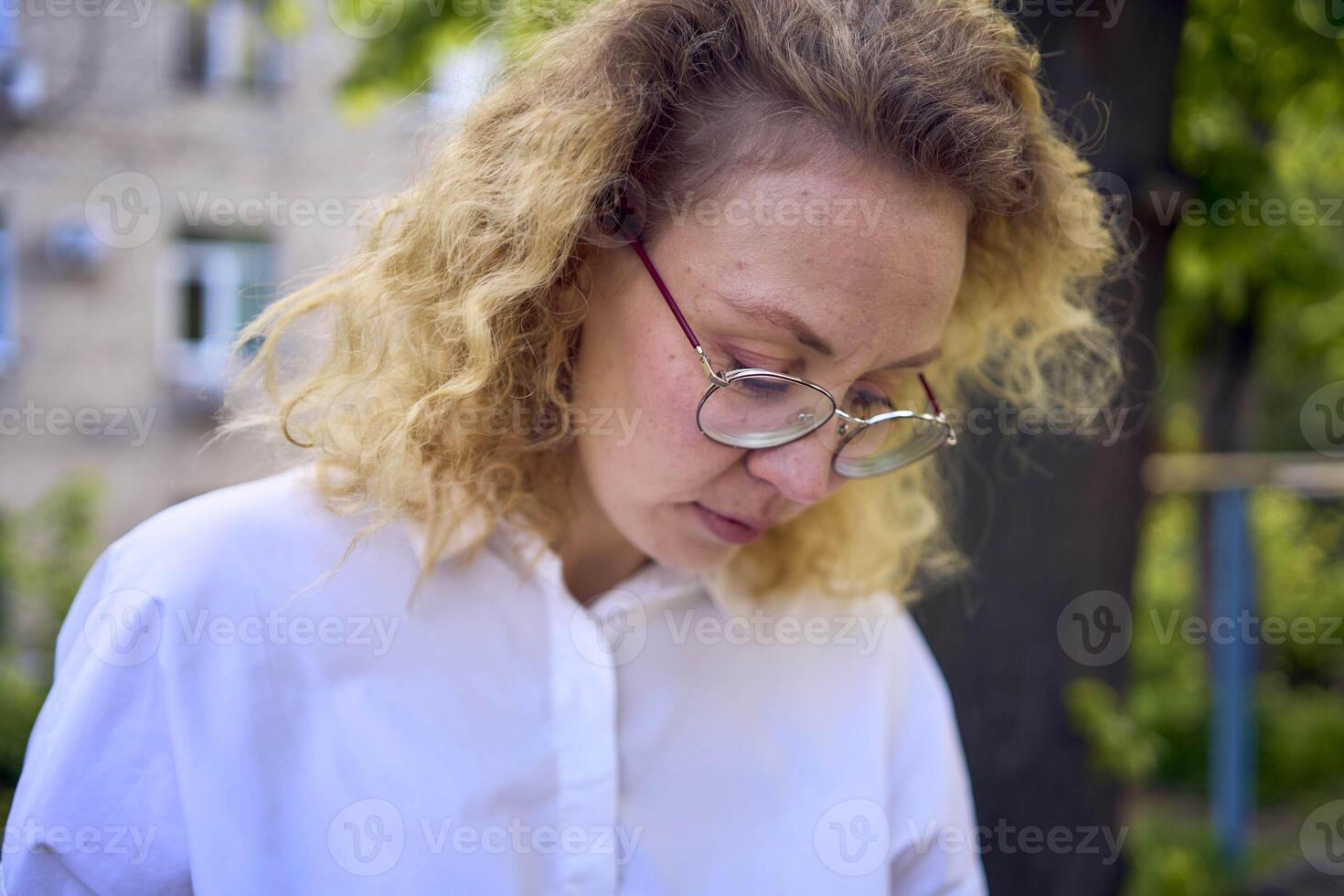 middle age woman in 70s, 80s style clothes with a coffee stain on her blouse in front of gray houses of the 70s photo