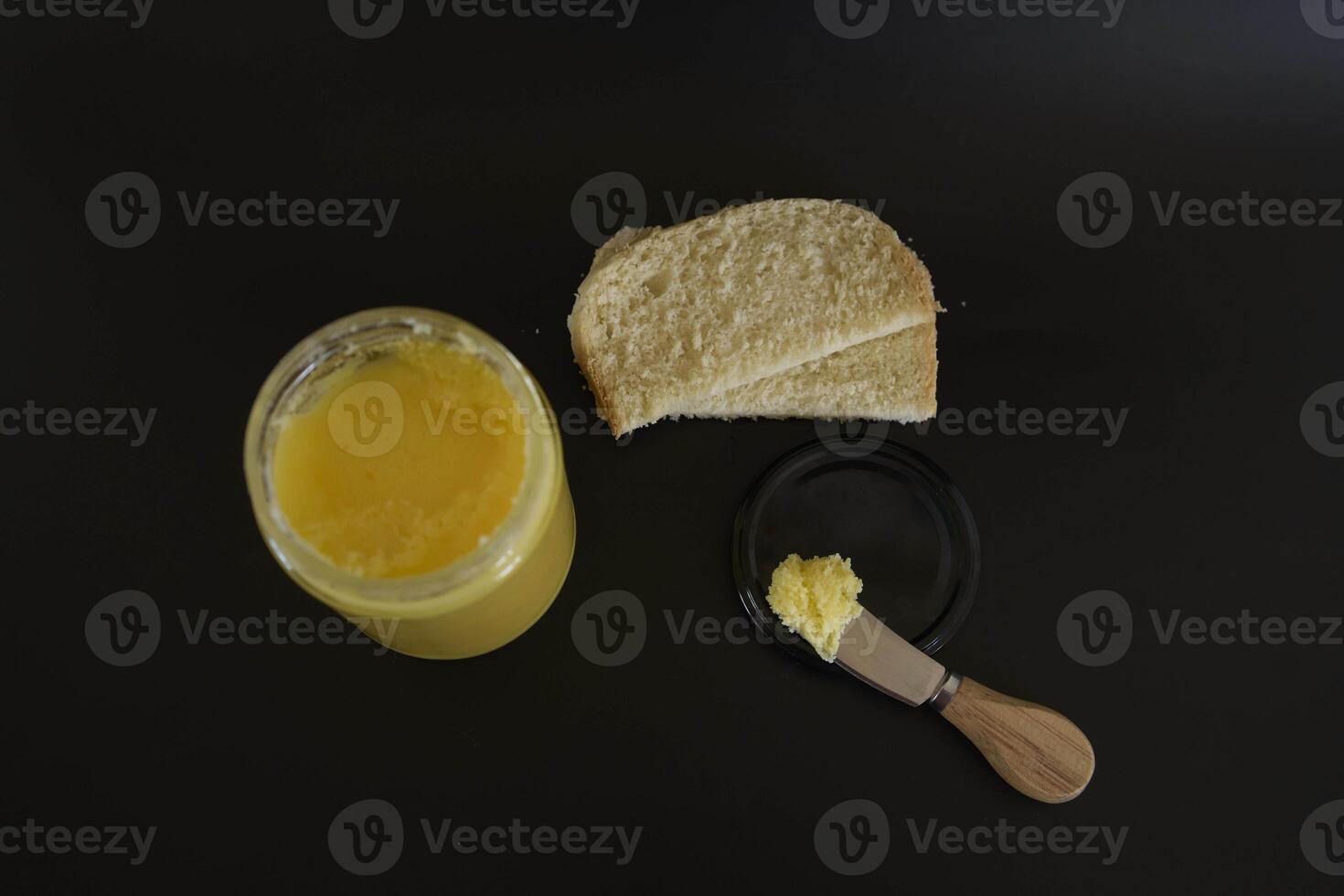 butter ghee in a transparent jar with homemade bread on a black background photo