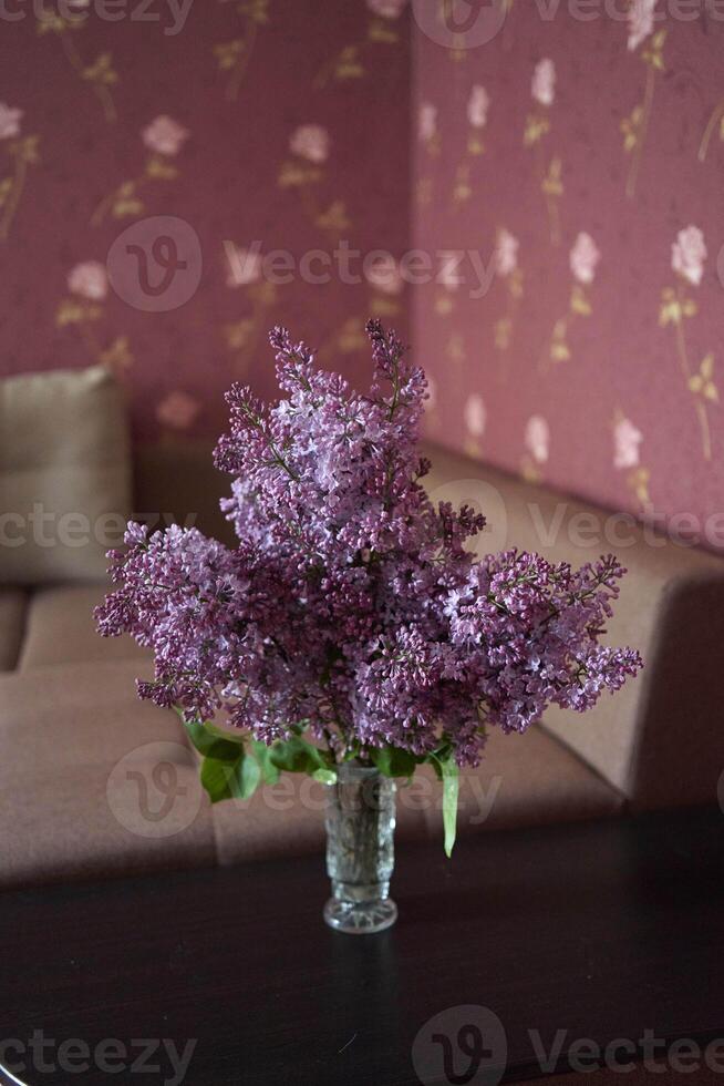 a bouquet of lilacs in a crystal vase in the interior photo