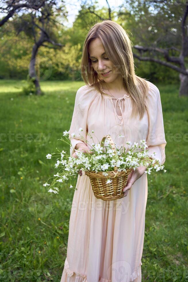 a portrait of a beautiful woman in a peach fuzz dress with a basket of flowers photo