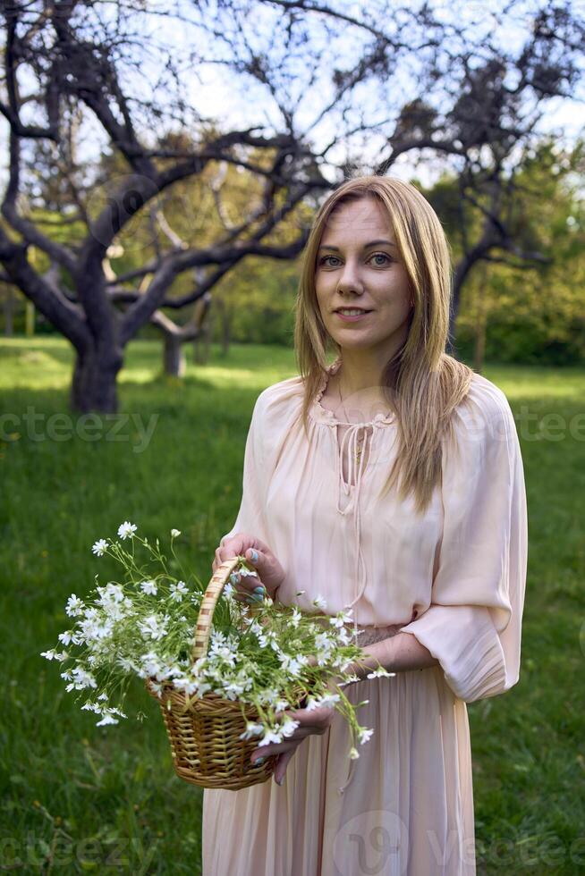 a portrait of a beautiful woman in a peach fuzz dress with a basket of flowers photo