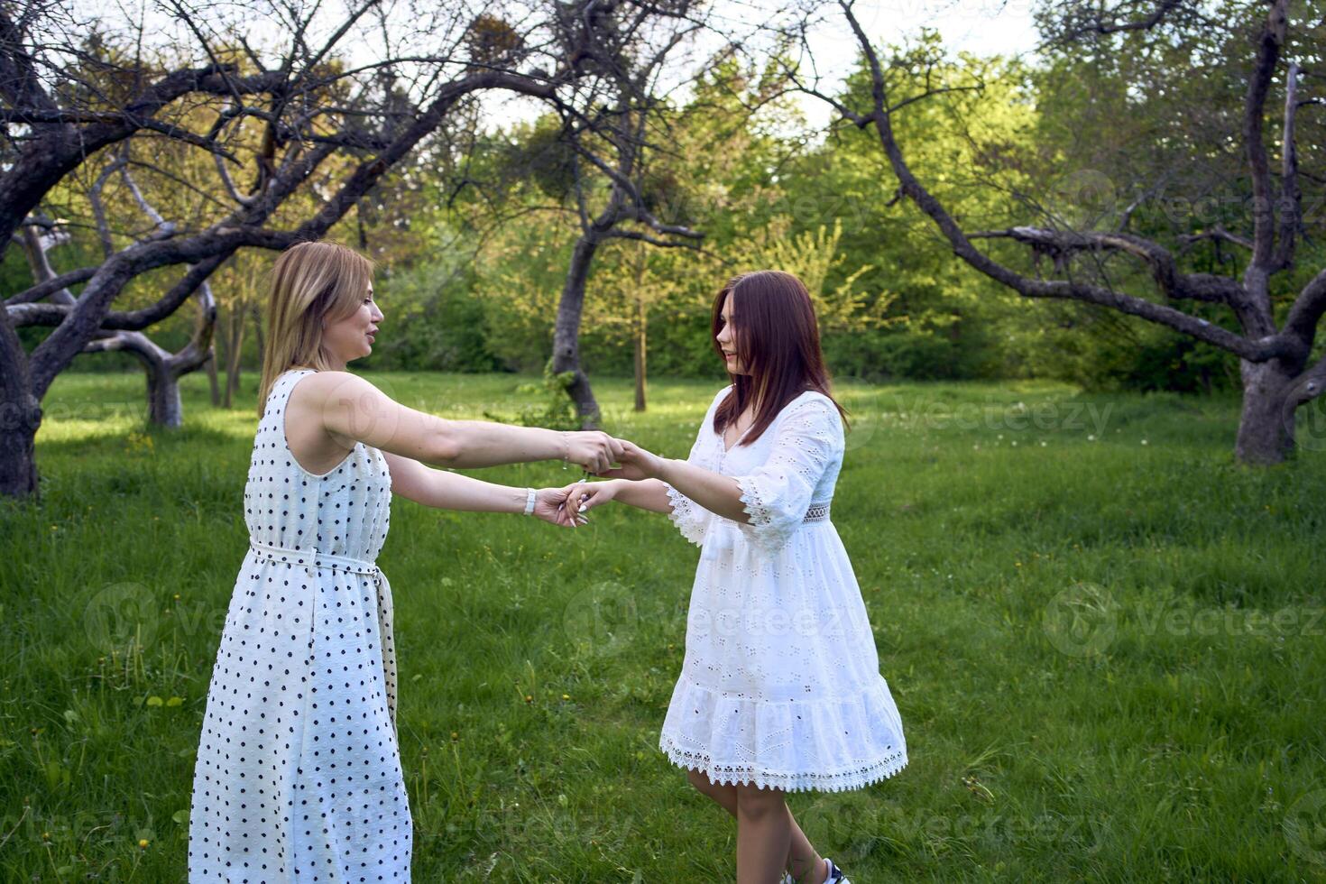 a mother and her teenage daughter are hugging and playing in the garden photo