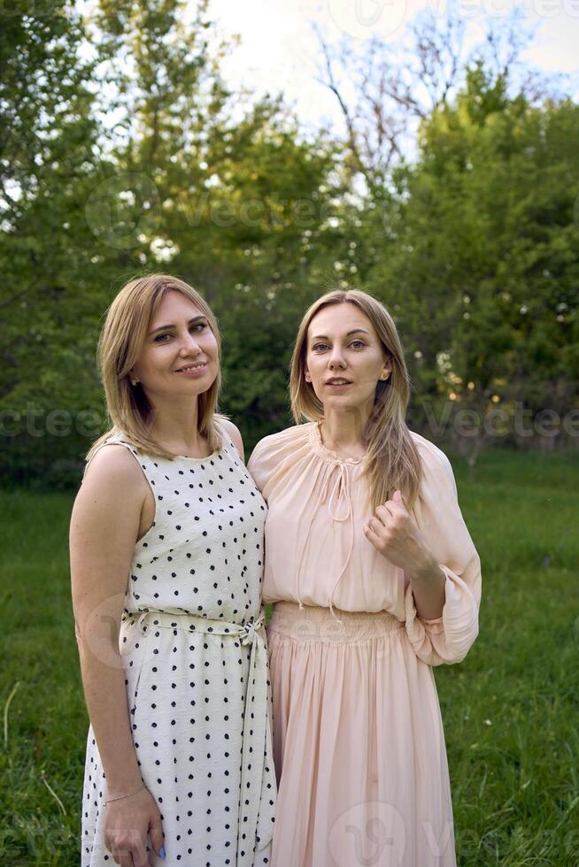 two women hug and pose against the background of nature photo