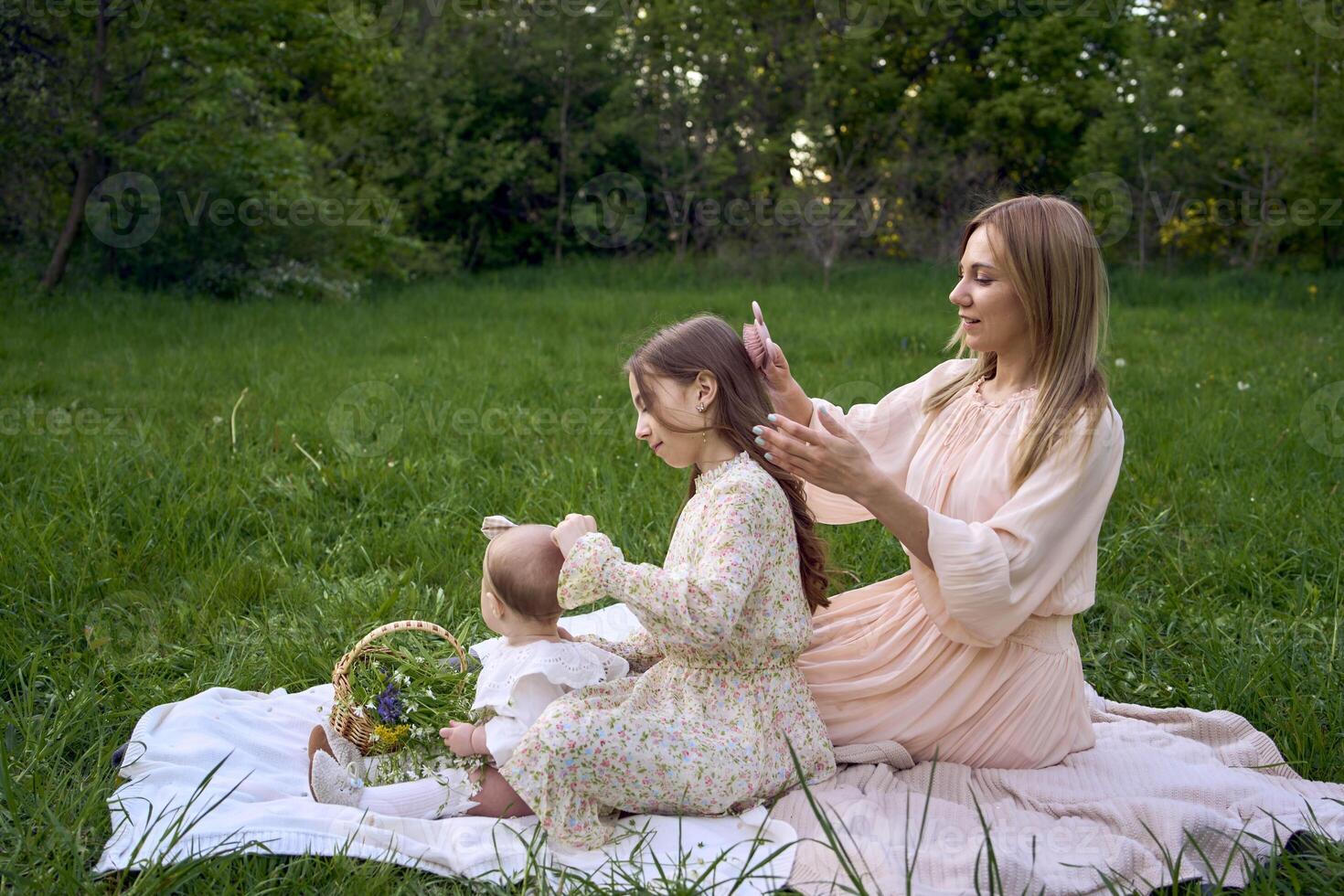 the mother combs the older daughter's hair, and the older daughter combs the younger daughter's hair photo