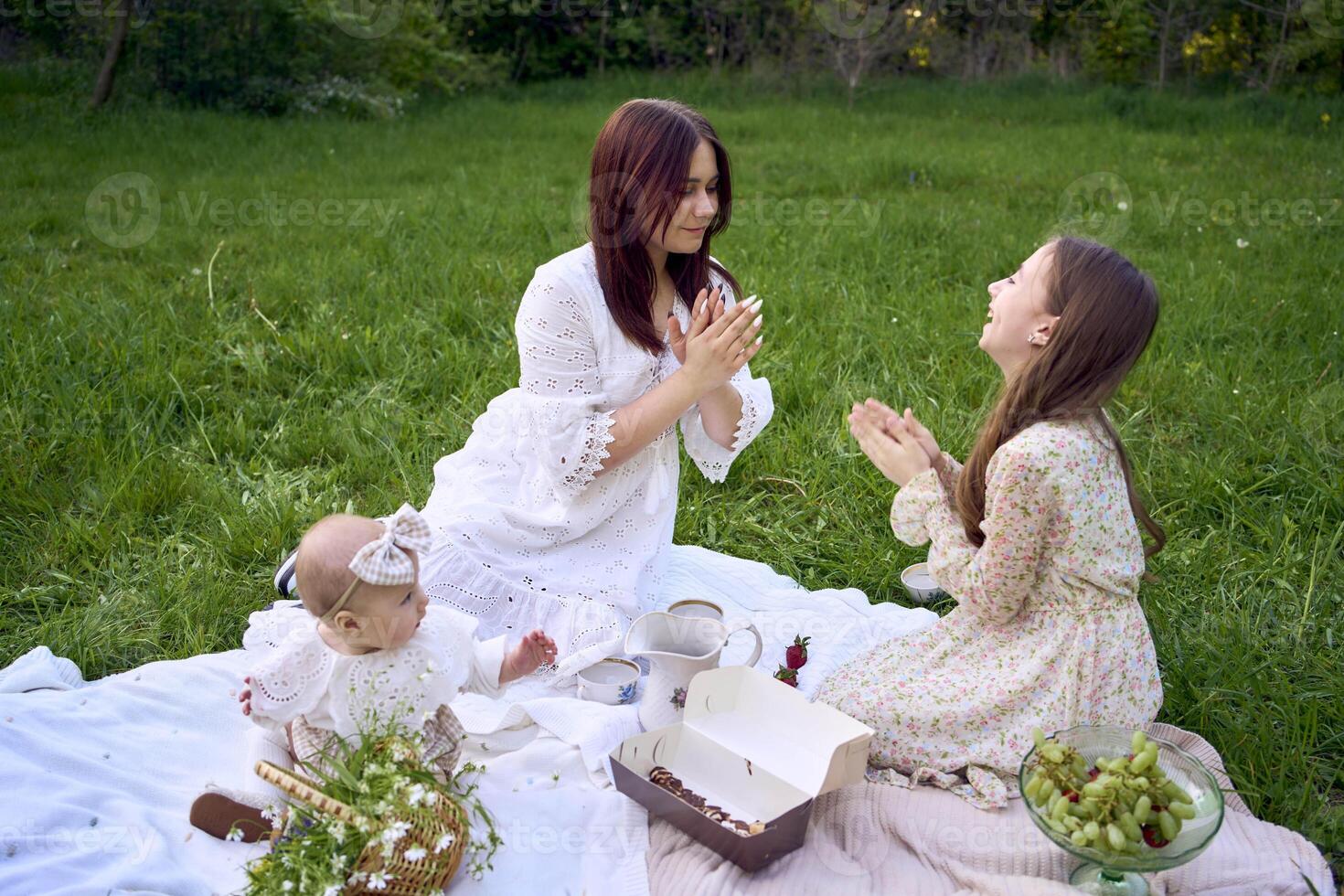 sisters of different ages hug each other tenderly on a picnic in the garden photo