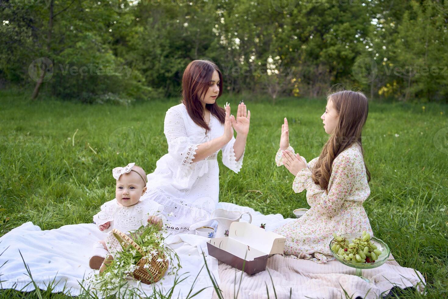 sisters of different ages hug each other tenderly on a picnic in the garden photo