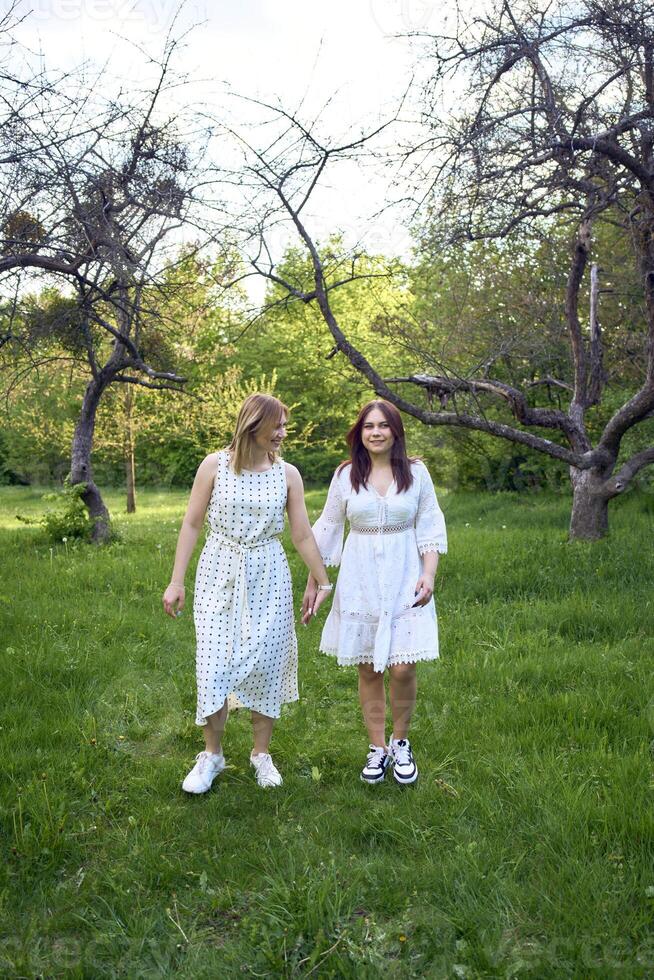 a mother and her teenage daughter are hugging and playing in the garden photo