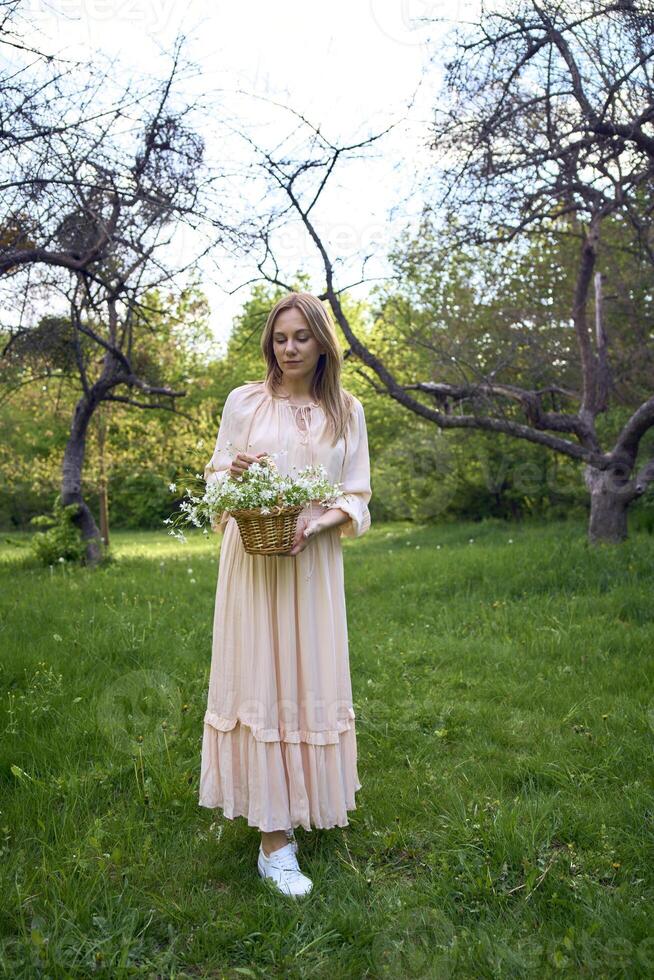 a portrait of a beautiful woman in a peach fuzz dress with a basket of flowers photo