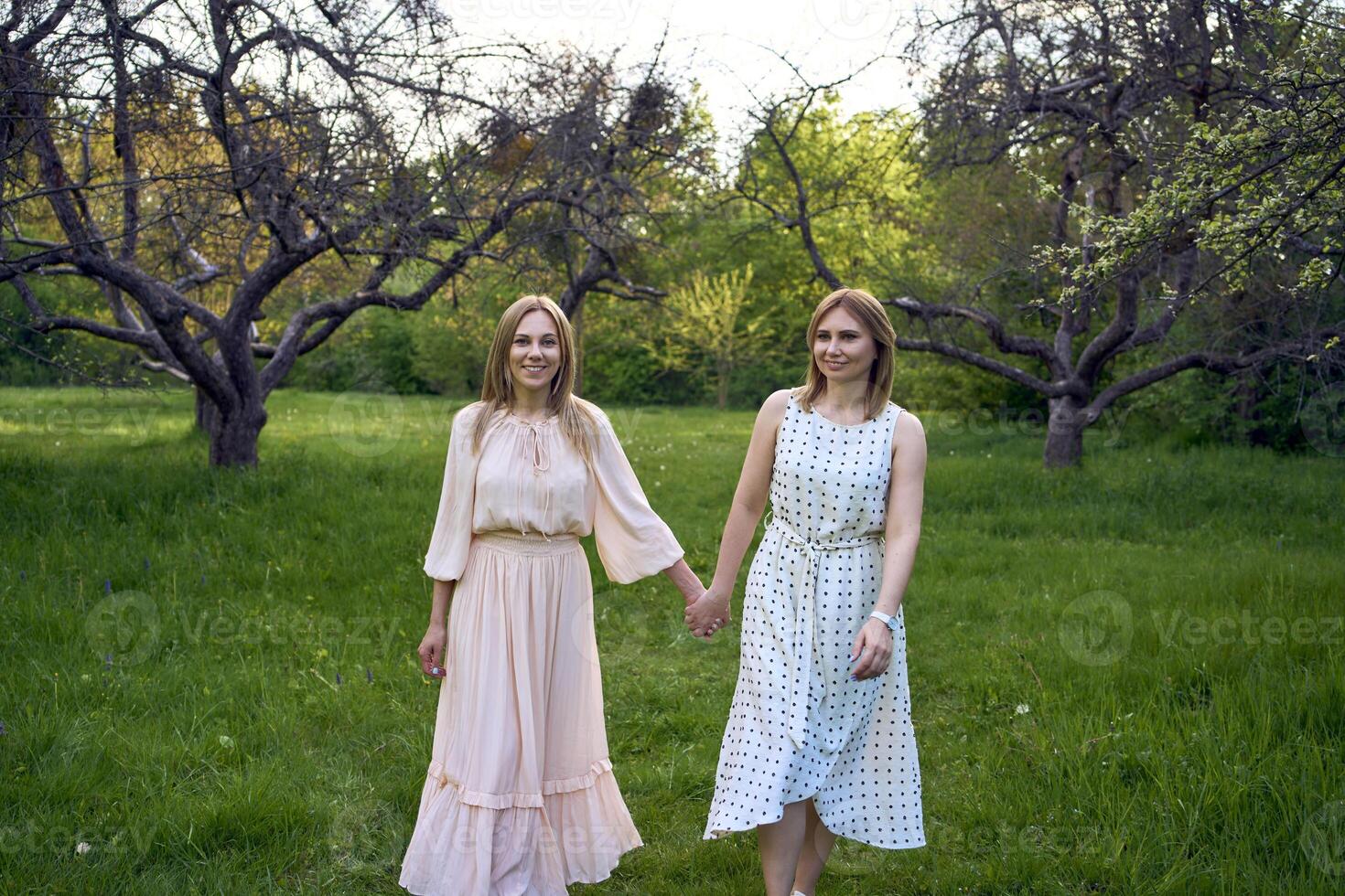 two women hug and pose against the background of nature photo