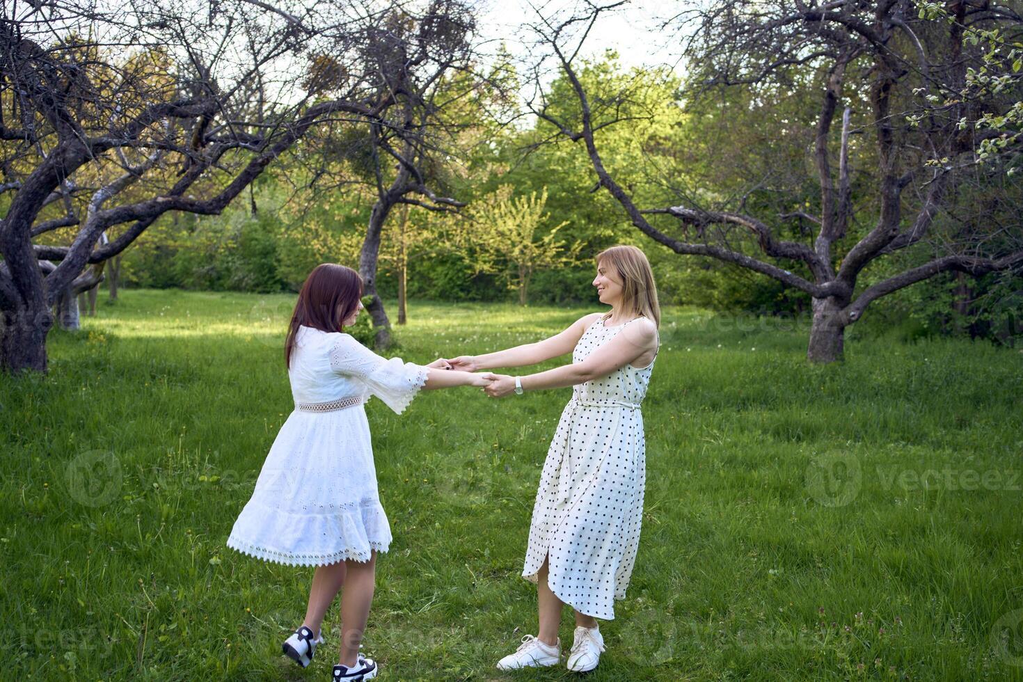 a mother and her teenage daughter are hugging and playing in the garden photo