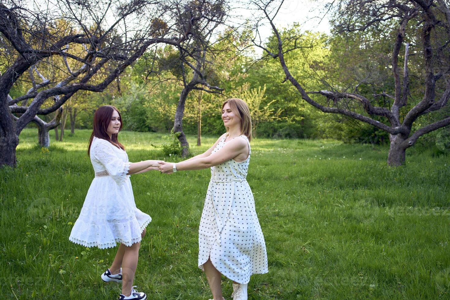 a mother and her teenage daughter are hugging and playing in the garden photo