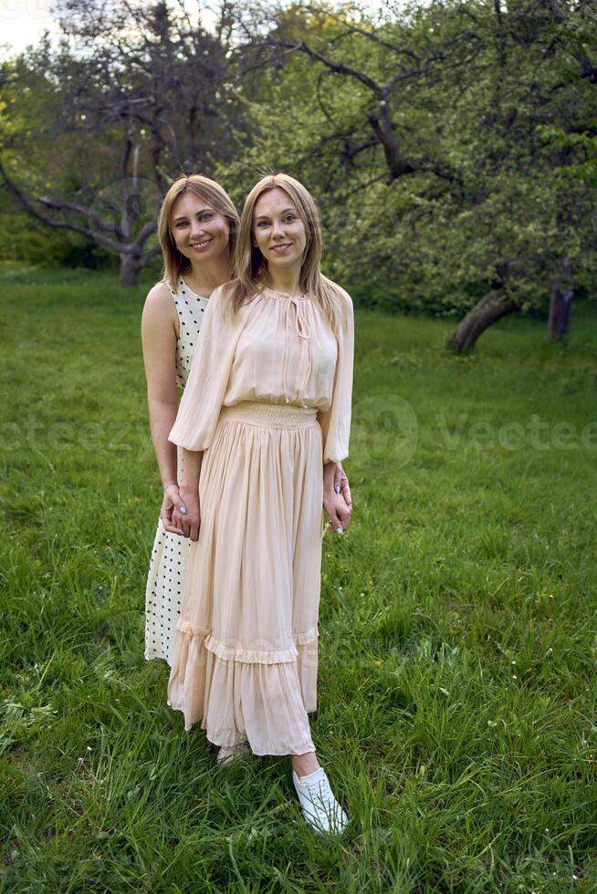 two women hug and pose against the background of nature photo