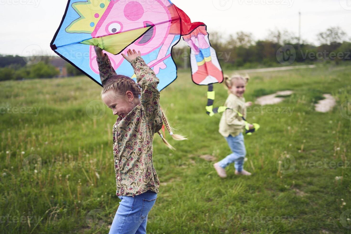 two little sisters and mother run and launch a kite in a field photo