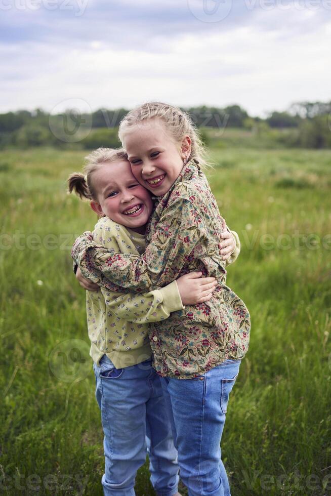 sisters hug and protect each other from the wind in the field photo