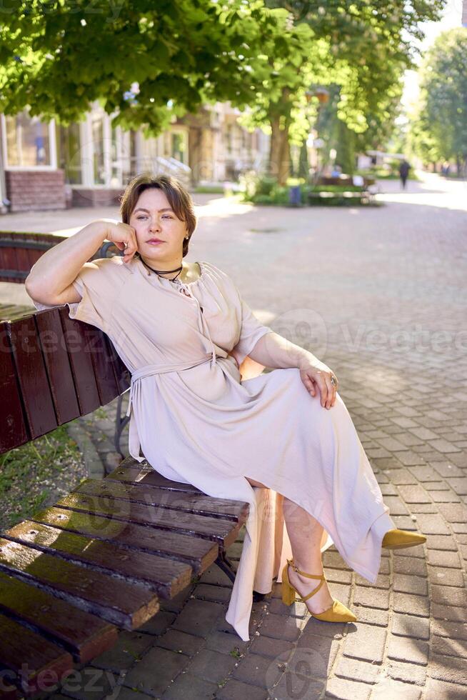 a plus size woman in a peach fuzz dress walks through the morning city photo