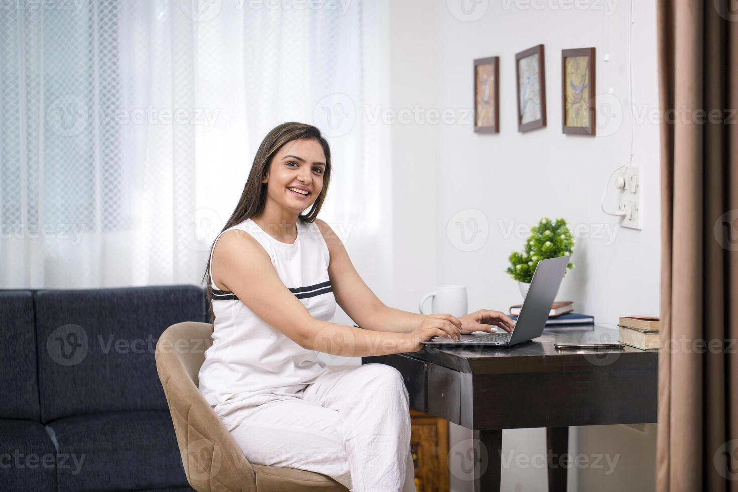 Smiling Female Sitting In Front Of Laptop While Posing On Camera Screen photo