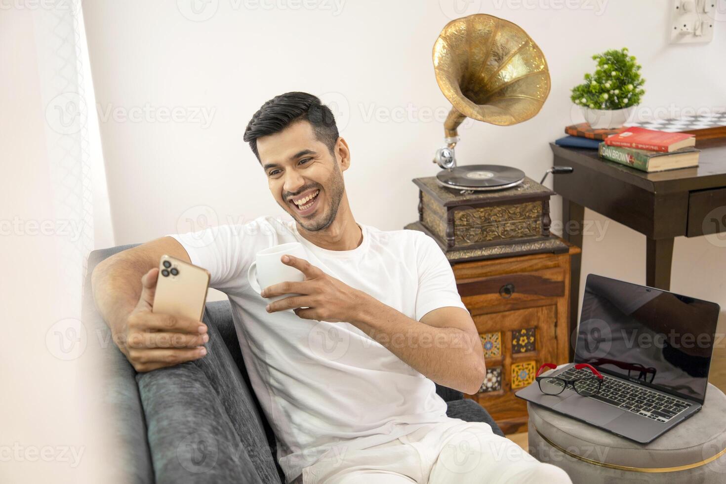 Attractive Man Smiling Watching Clip On Mobile Phone While Drinking Coffee photo
