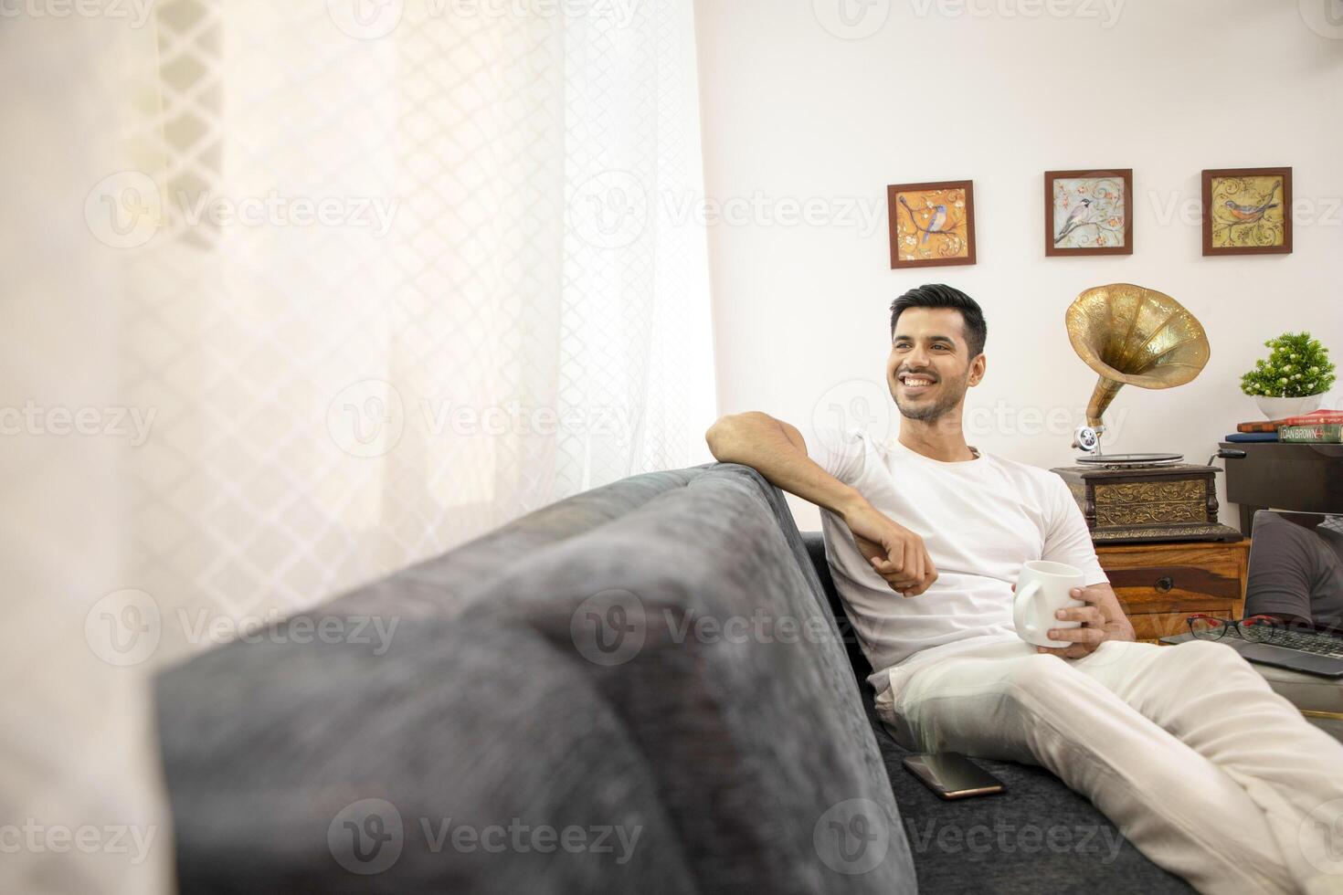 Guy In Tshirt Sitting In His Own Thought While Holding Coffee Mug In Hand photo