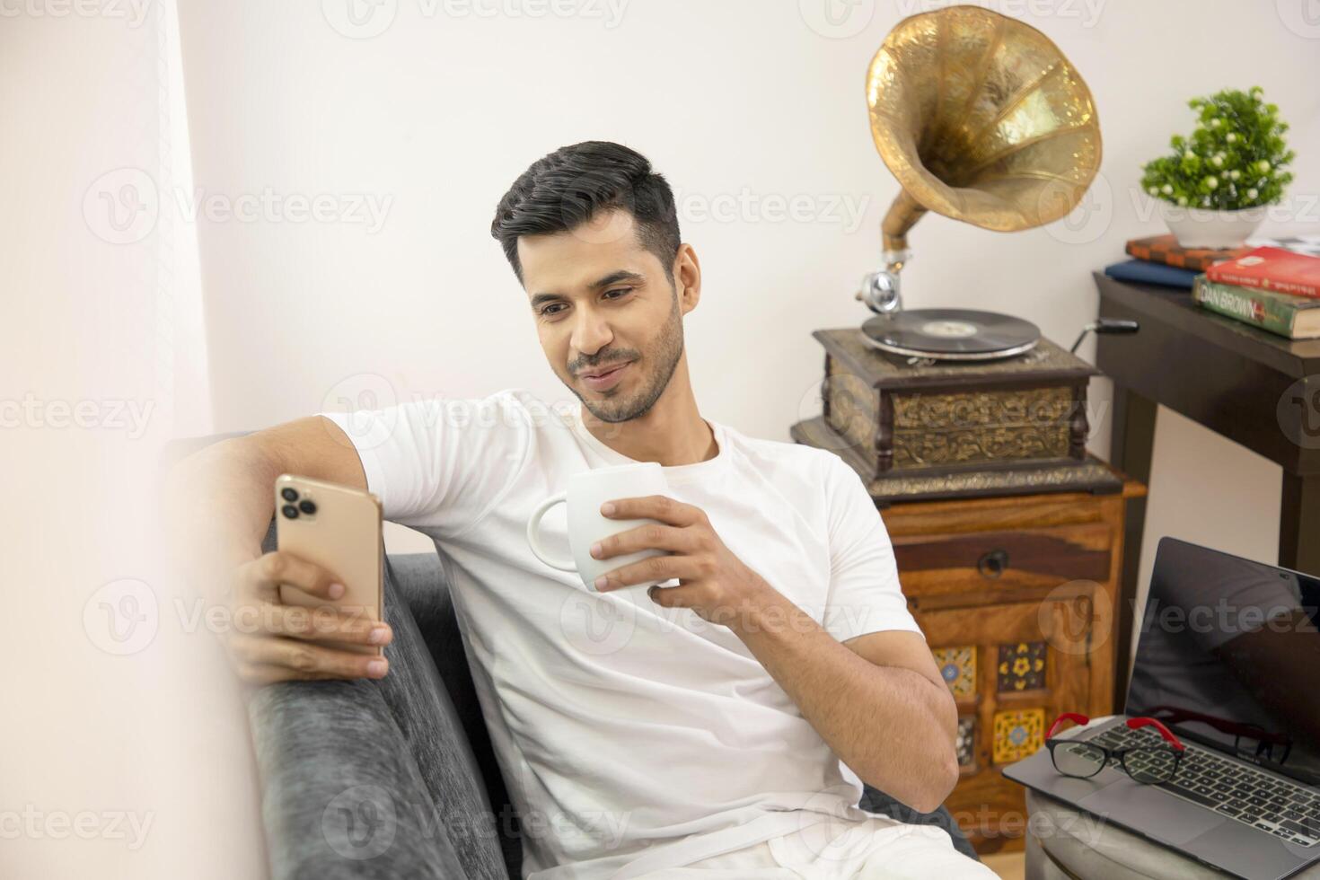 Sweet Man Sitting On Sofa While Watching Reel On His Smart Phone photo