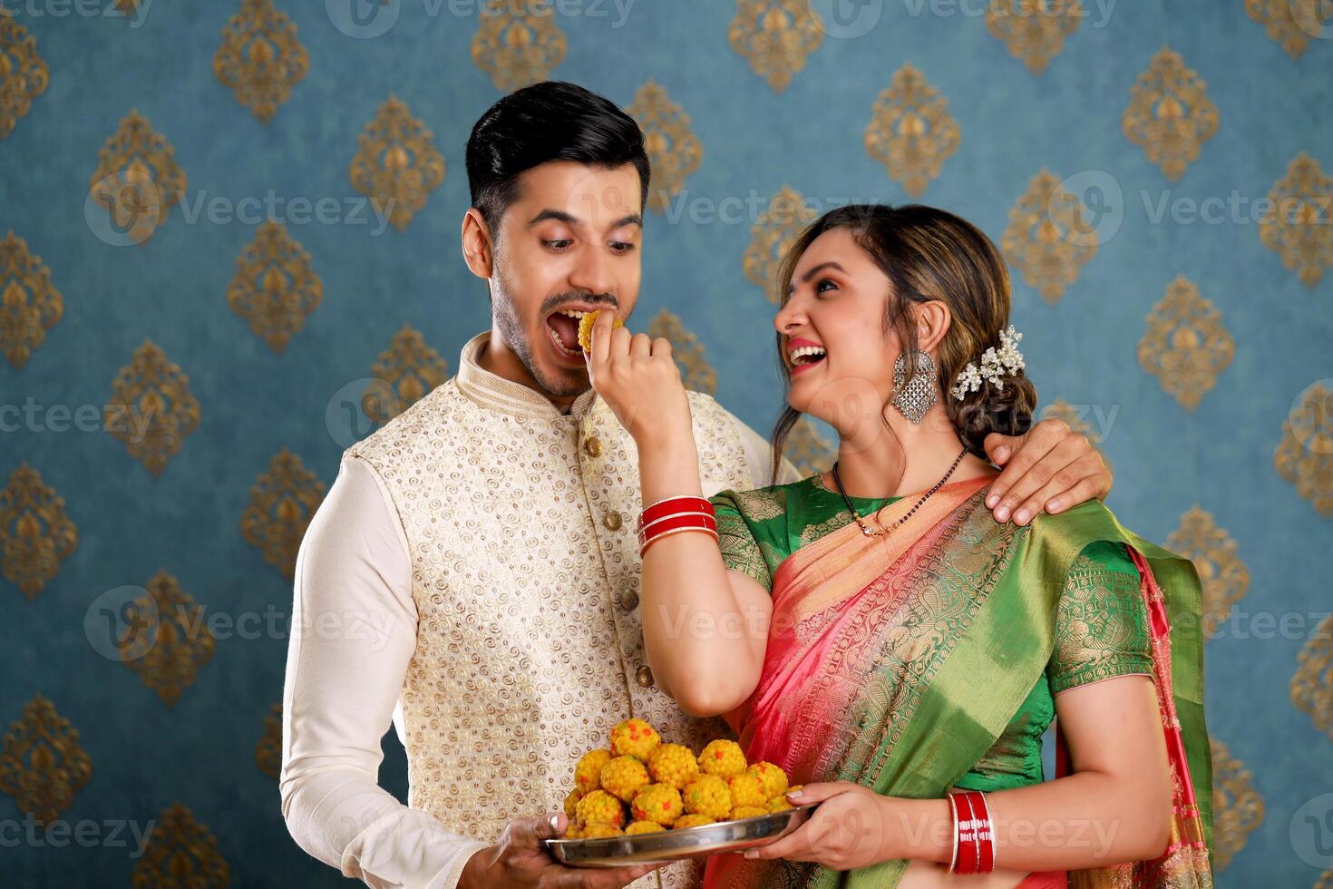 A Stock Photo Of A Cute Romantic Couple Enjoying Laddus At The Diwali Celebration While Dressed Traditionally