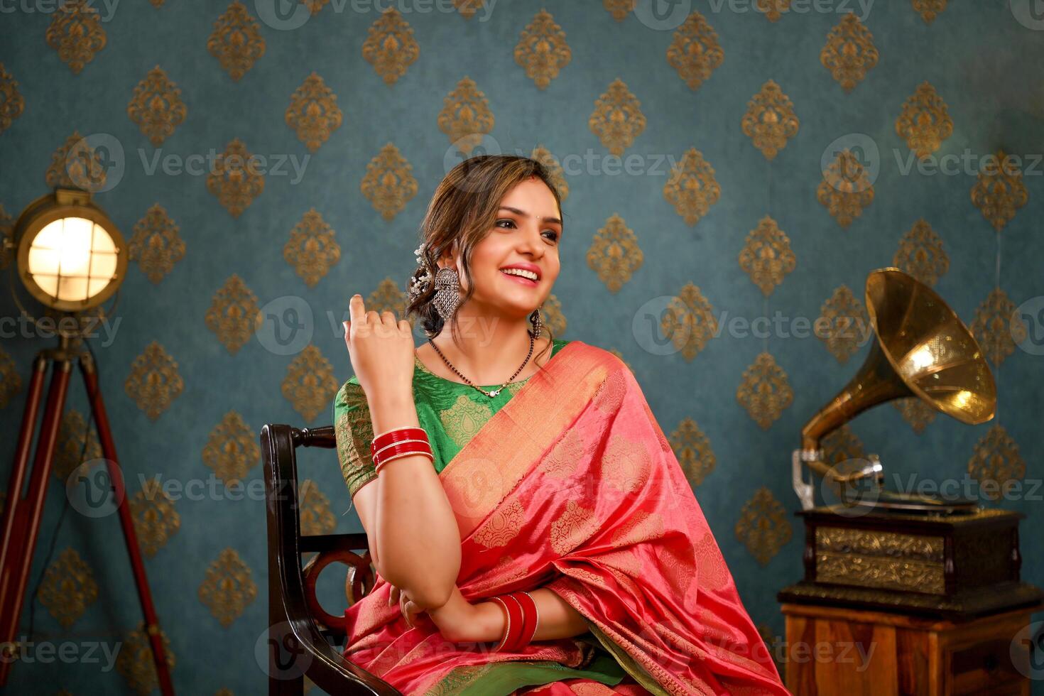 Top Female Model Seated On Chair And Posing For The Camera While Wearing A Saree photo