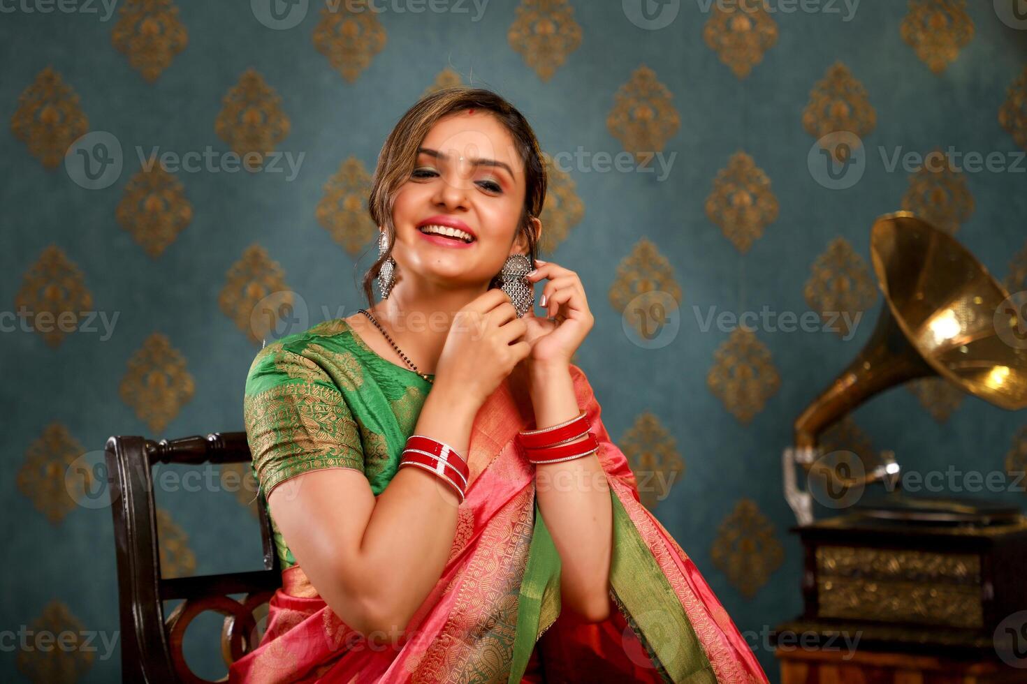 A Beautiful Woman In Traditional Indian Saree Sitting On A Chair photo