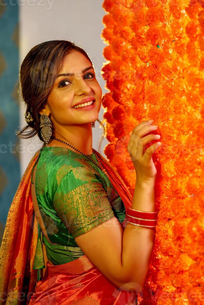 A Cute Housewife In Saree Posing Next To Flower Decorated Wall photo