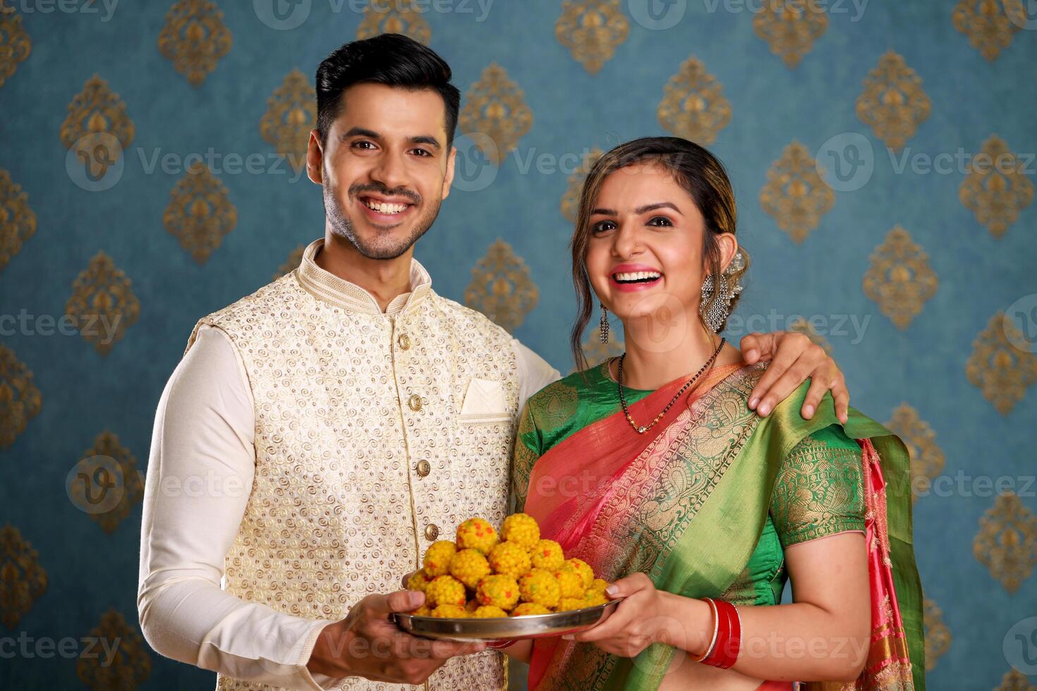 Smiling Beautiful Couple In Traditional Indian Attire Holding Plate Of Ladoo photo