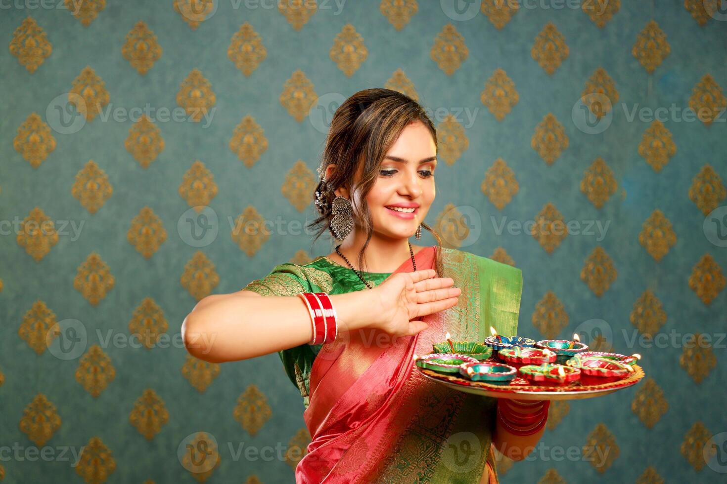 A Nice-Looking Woman In Traditional Indian Attire Holds A Plate Of Diyas During The Celebration Of Diwali photo