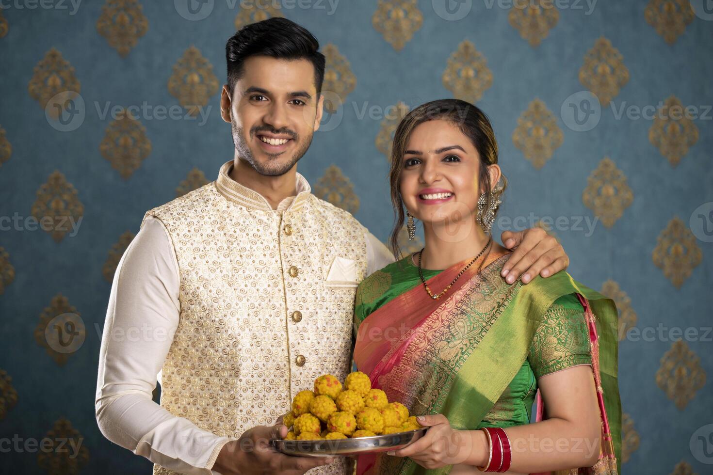 Nice Couple Holding Laddu Plate While Posing In Front Of Camera photo