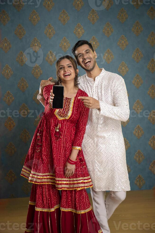 Picture Of An Adorable Couple Wearing Traditional Indian Attire Holding A Plate Of Ladoos In Their Hands And Smile photo