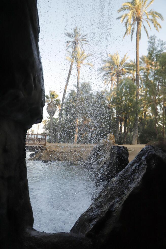 look through a whole in the rocks through the waterfall on the trees photo