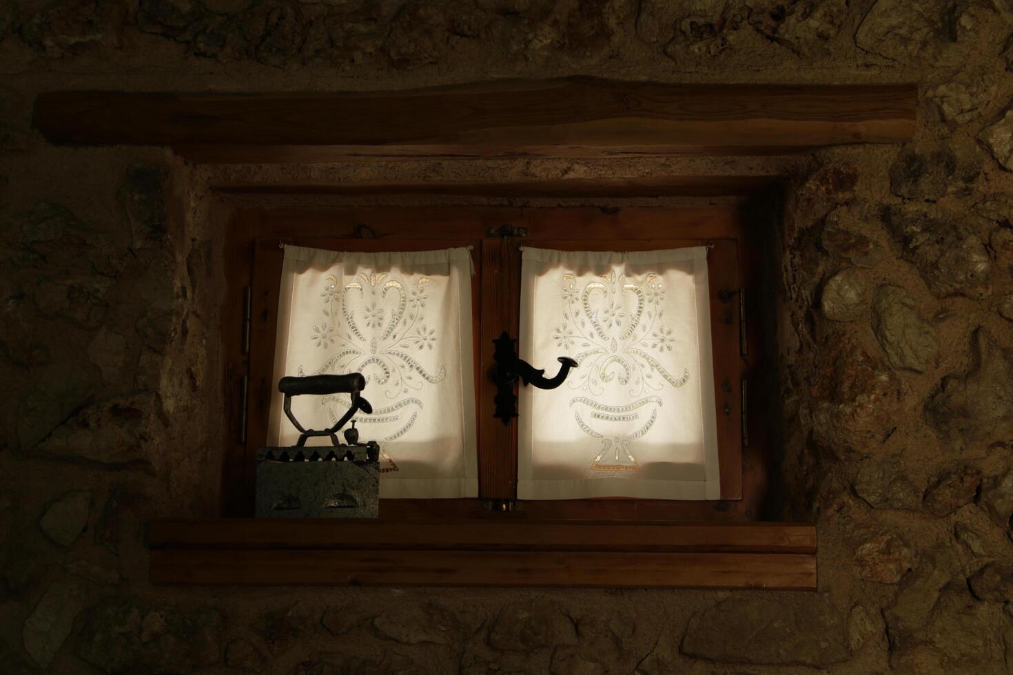 old iron in a window with a curtain photo