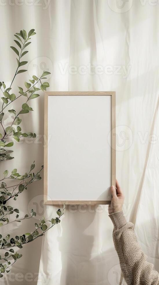 A mockup of a minimalistic A4 frame A woman's hand holding the wooden A4 frame visible danish pastel aesthetic in the room photo