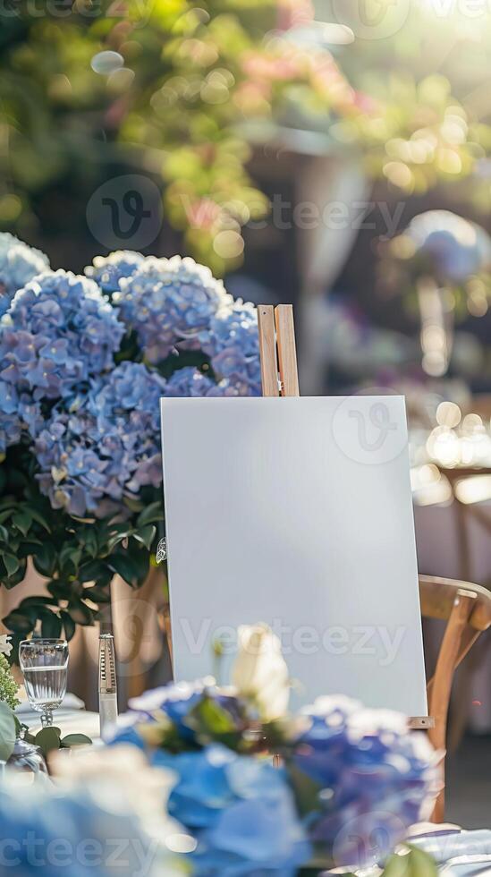 A white blank horizontal poster on easel in front of wedding reception tables with pastel blue and purple colors hydrangea flowers photo