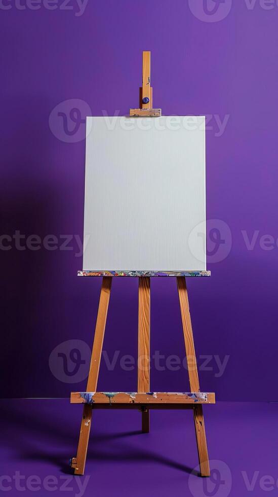 An easel with a white canvas on a stretcher stands in a clean purple blue room photo