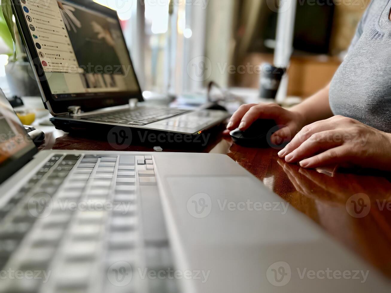freelance girl working on laptop and clicking wireless digital mouse with digital tablet on office desk, close up, dark tone photo