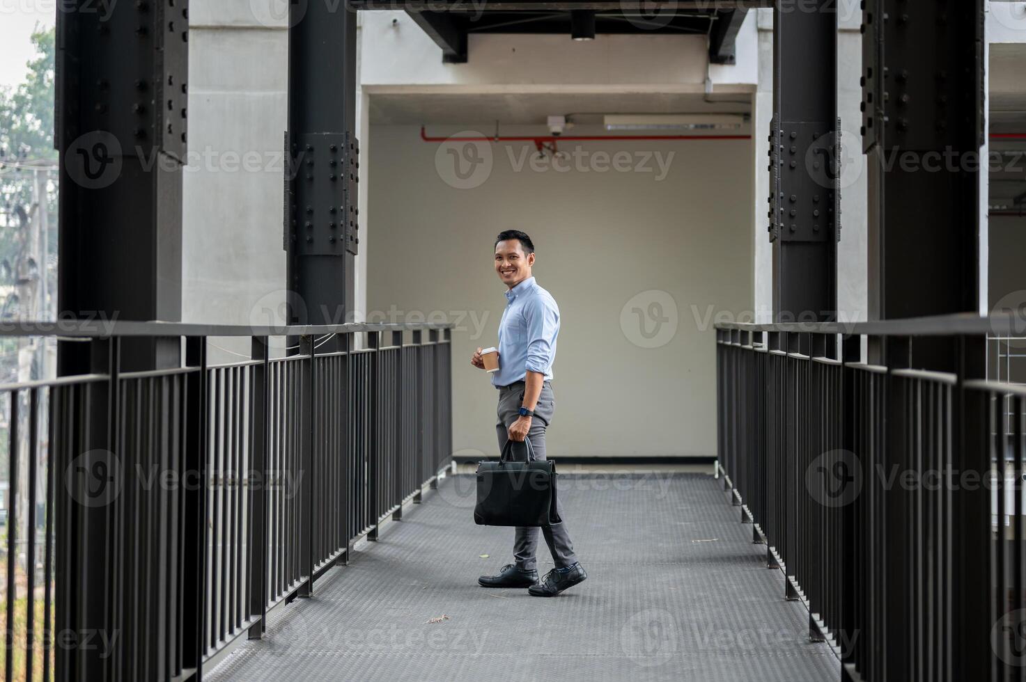 A confident, experienced Asian millennial businessman stands on a company building corridor. photo