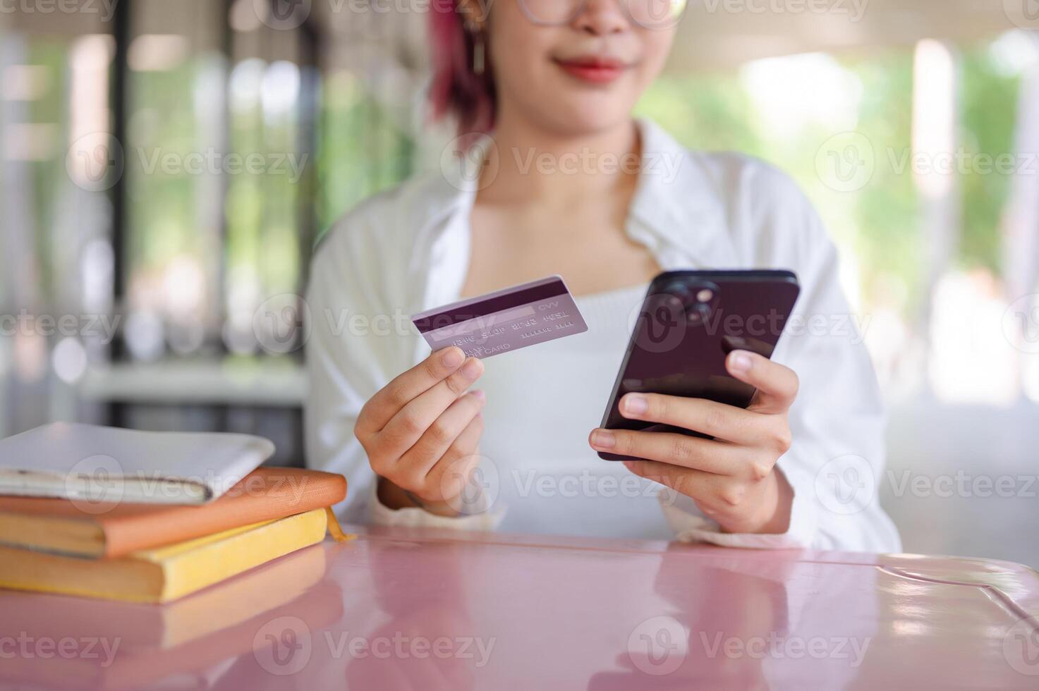 A cropped image of a female sits at a table in a cafeteria using a mobile banking app. photo