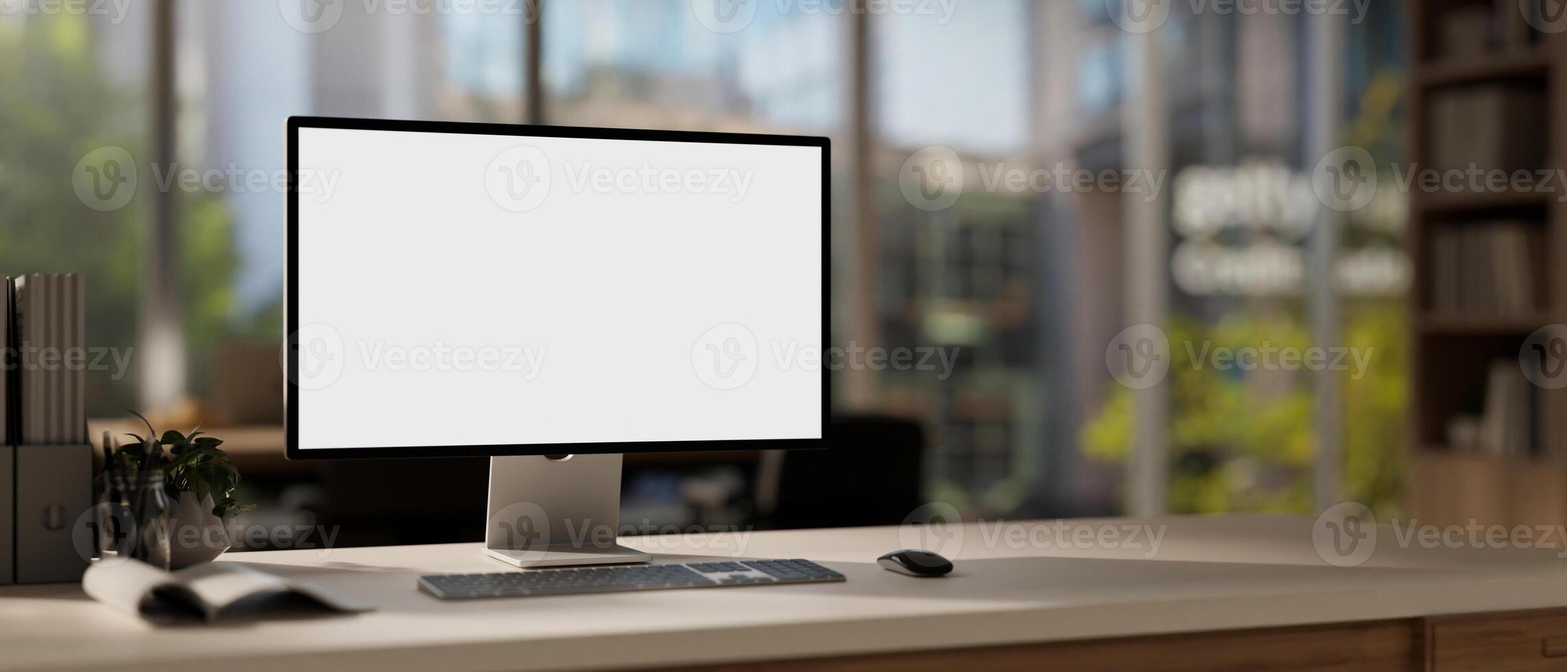 A computer mockup with a white screen and office supplies are arranged on a table in a modern office photo
