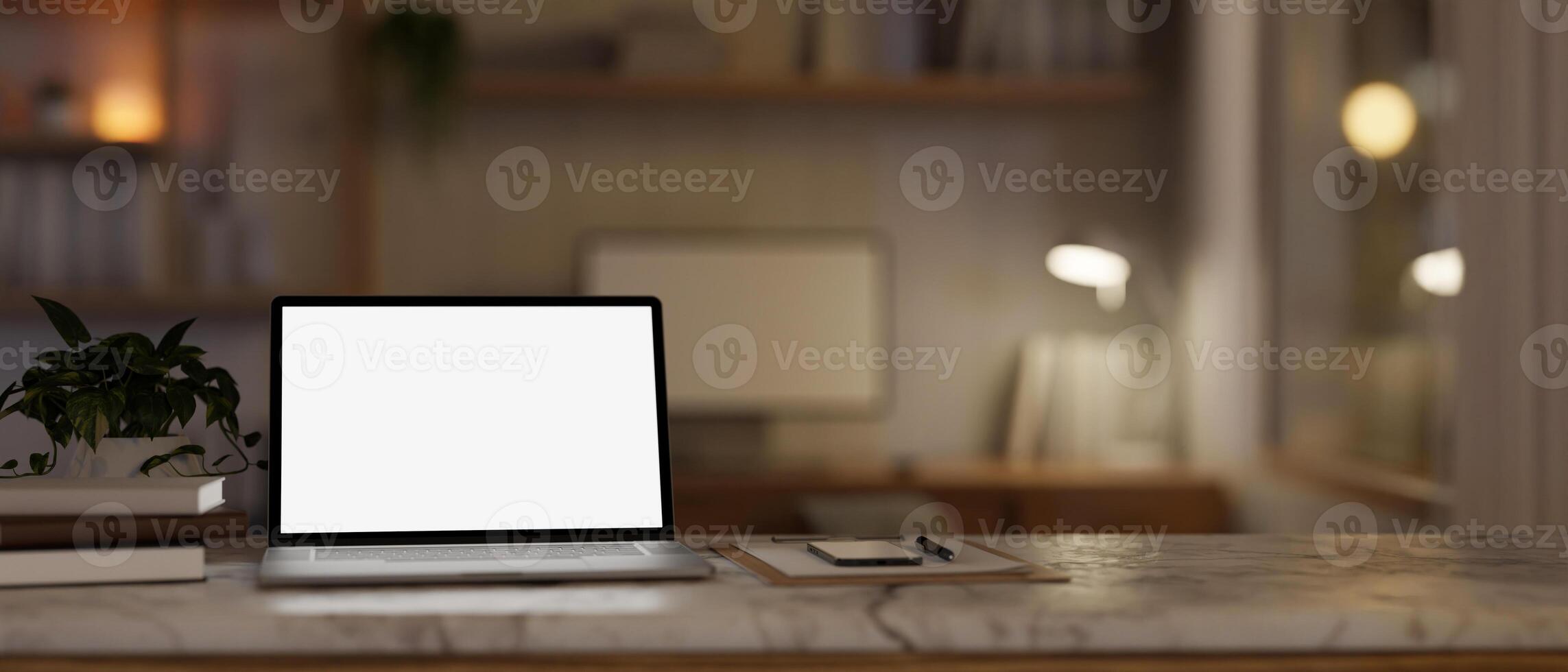 A white-screen laptop computer mockup on a white marble table in a cosy home office at night. photo