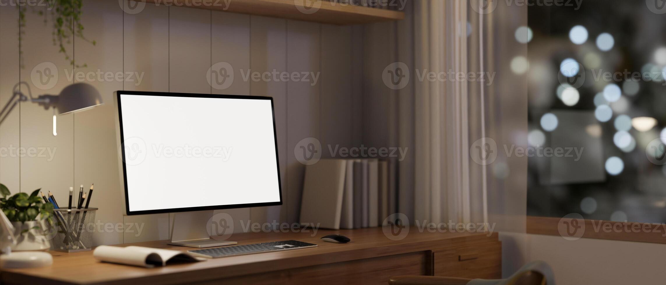A white-screen computer mockup and decor on a wooden desk in a cosy minimalist home office at night. photo