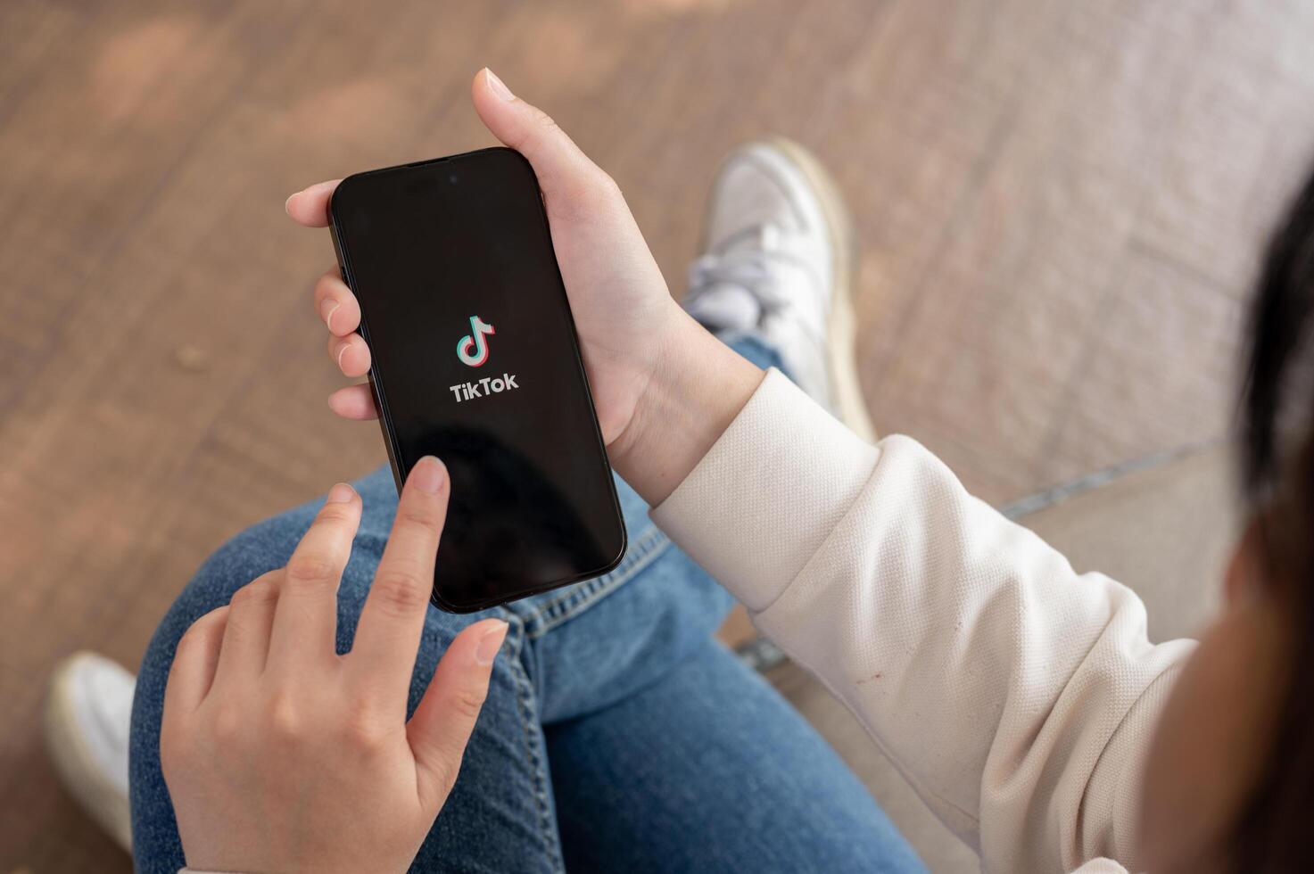 A close-up shot of a woman using the TikTok application on her iPhone while sitting outdoor. photo