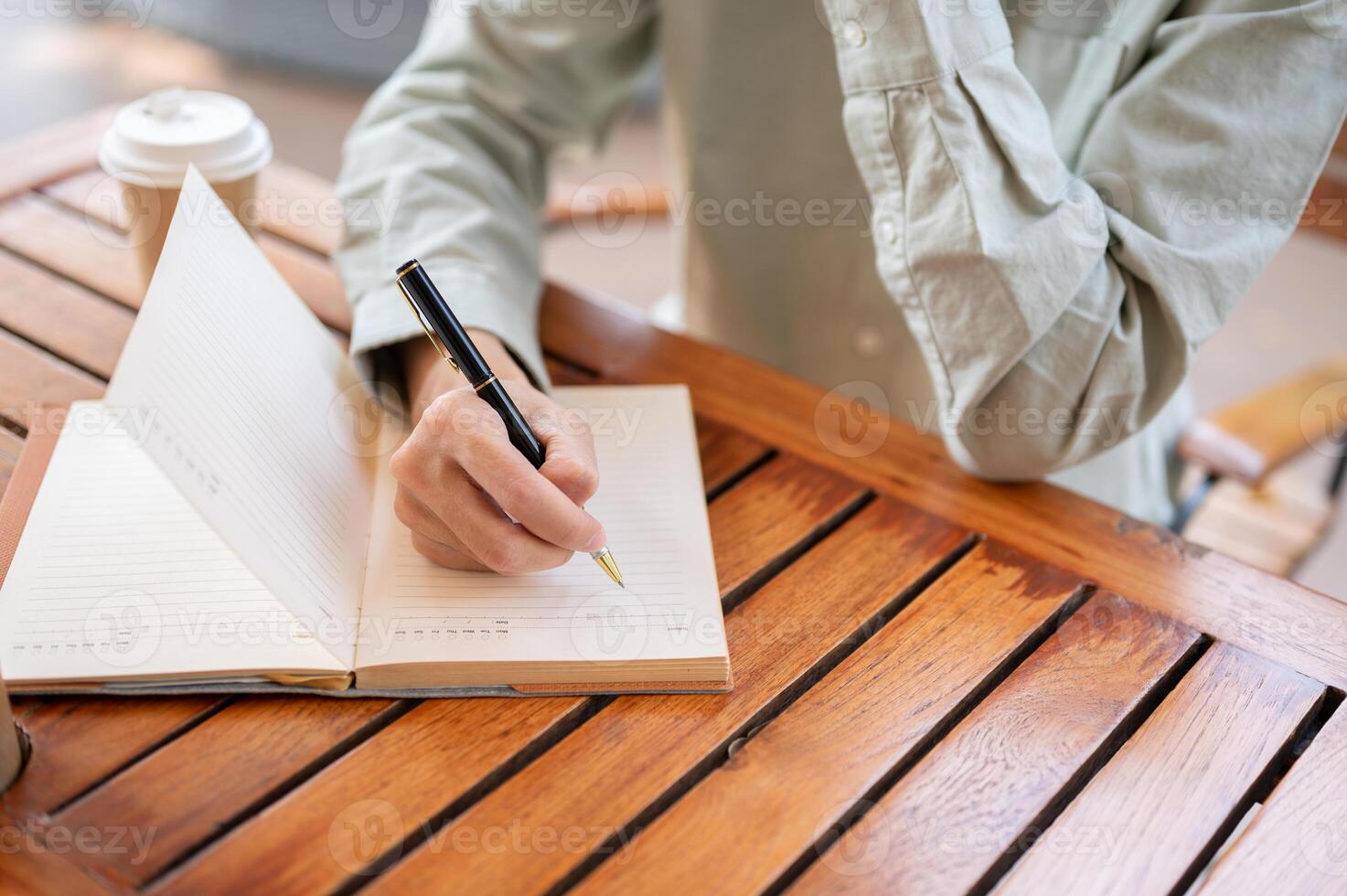 A man writing in his notebook, jotting down ideas, or keeping a diary while sitting in a cafe. photo