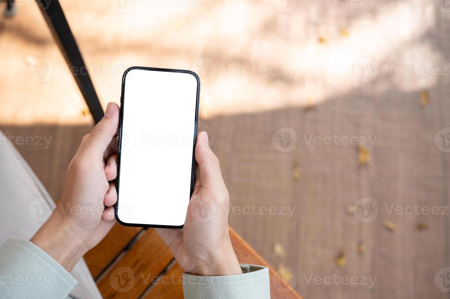 A man using his smartphone at a table in a cafe, with a white-screen smartphone mockup. photo