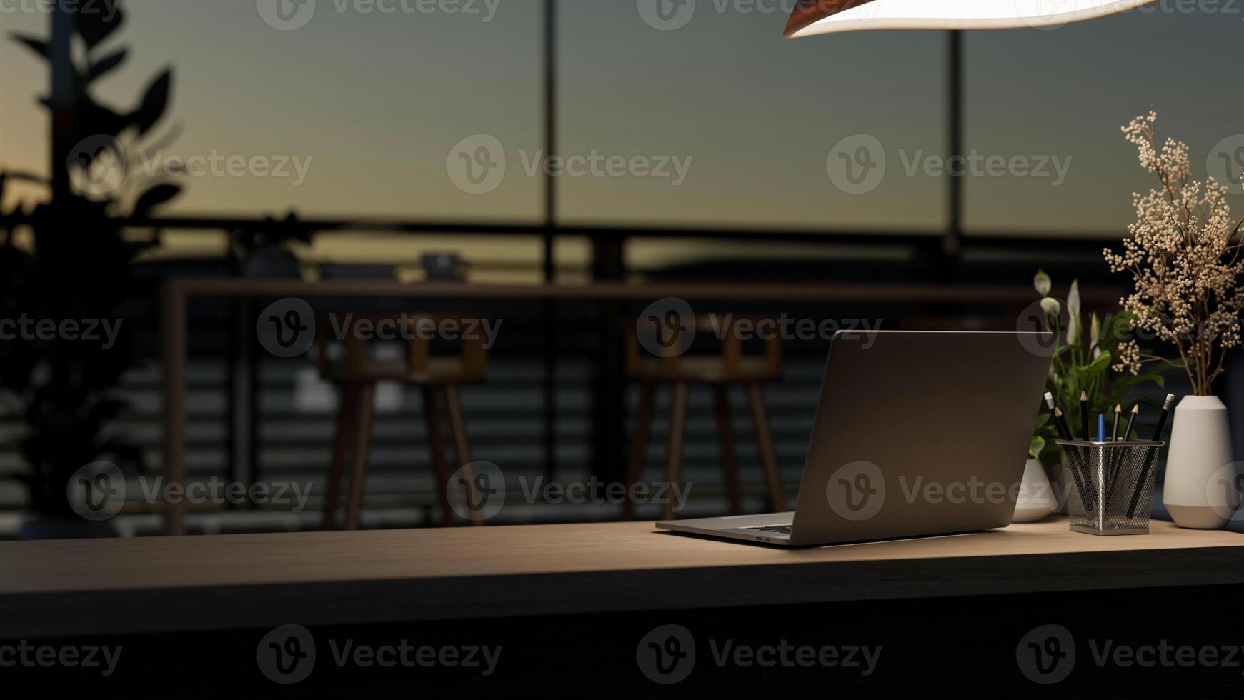 A laptop computer on a wooden desk under dim light in a contemporary dark co-working space at night. photo