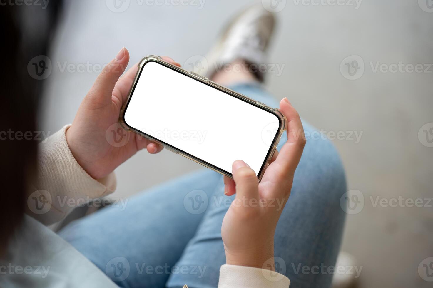 A woman holding a smartphone in a horizontal position, watching a or playing a mobile game. photo