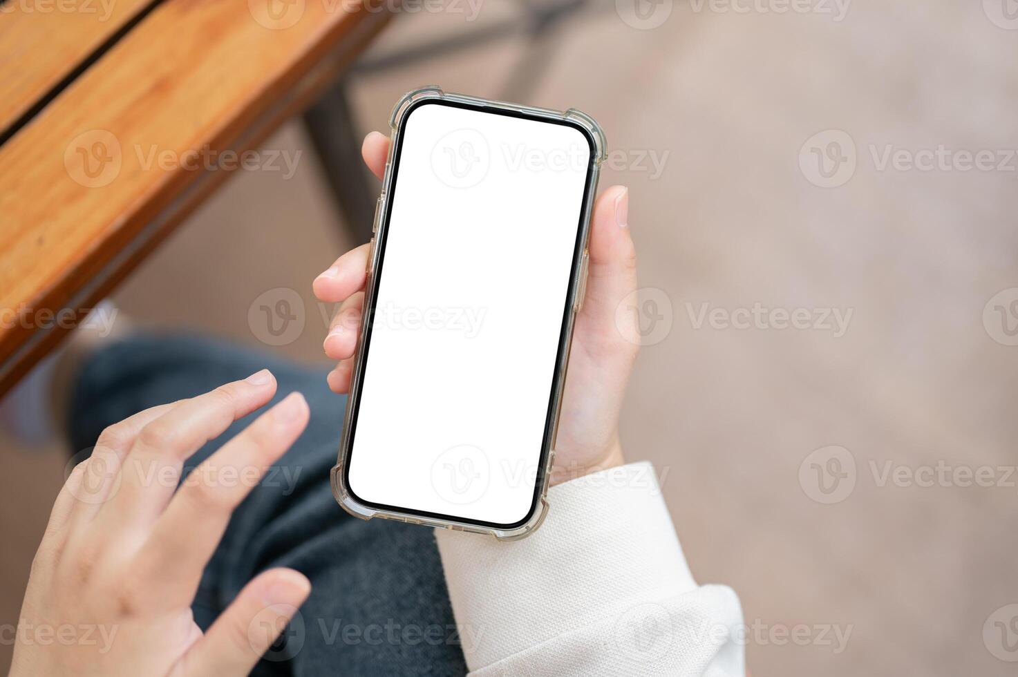 A close-up image of a woman in casual clothes using her smartphone at a table indoors. photo